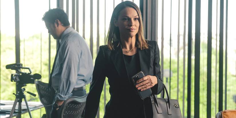 Rebecca, played by actor Kayla Wallace, wearing a black suit and smirking as she leaves in Landman