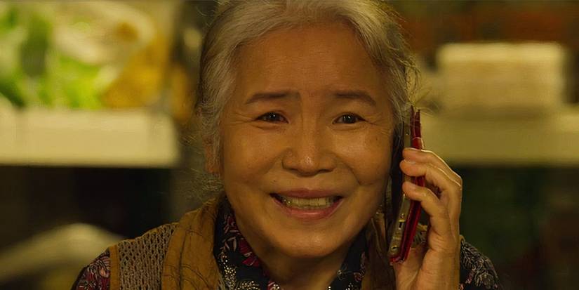 Cho Sang-woo's mother looks happy while talking on the phone in Squid Game