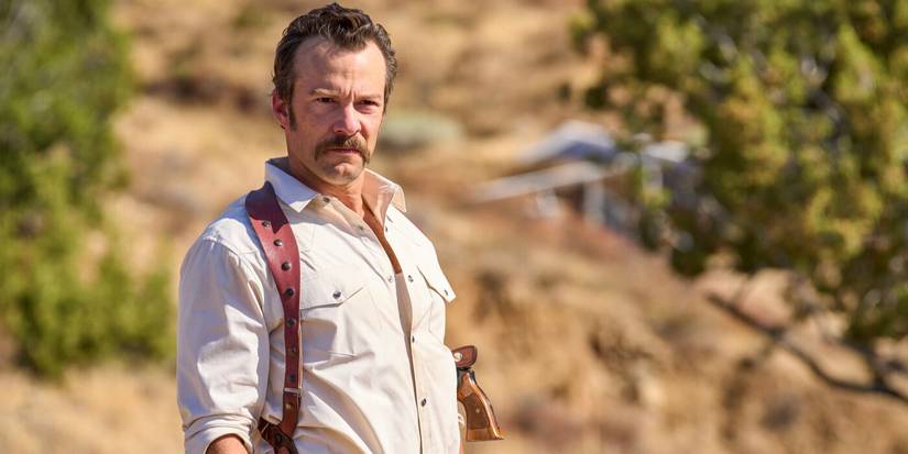 Mike Franks (Kyle Schmid) wearing a white shirt and his holster, in the desert in NCIS: Origins
