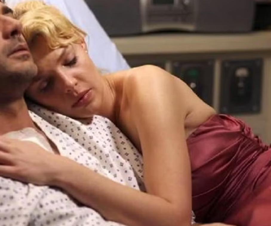 Izzy lays with Denny in his hospital bed in Grey's Anatomy.