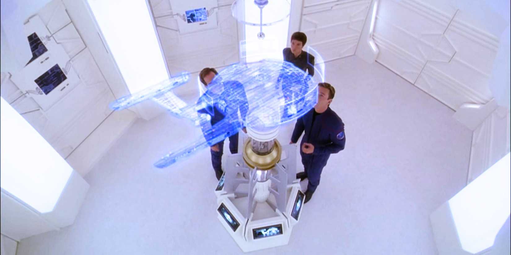 Captain Archer, T'Pol and Trip Tucker, all in uniform in a stark alien room with a holographic enterprise projected into the air from Star Trek Enterprise.