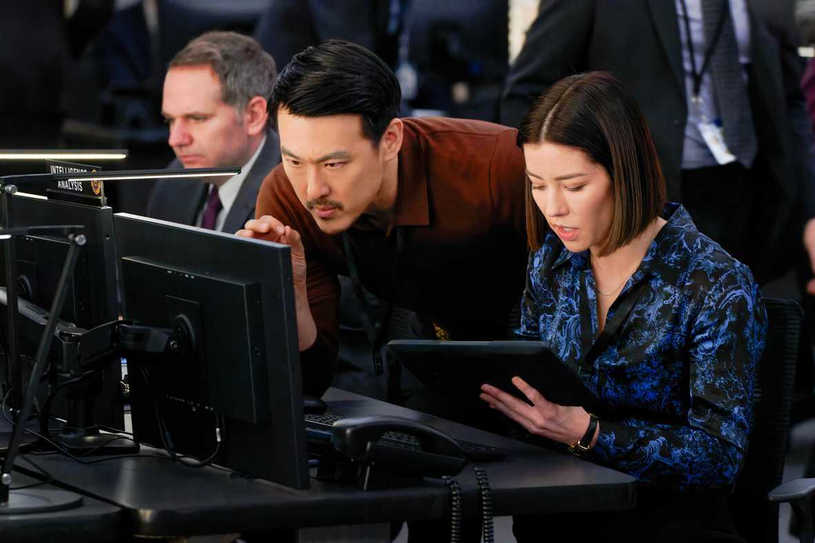 Two FBI analysts huddle around one computer, one holding a tablet, in FBI Season 7, Episode 11