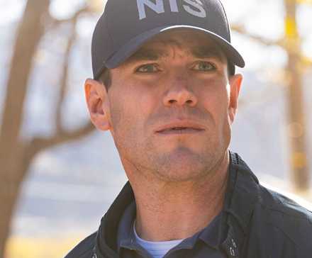 Young Gibbs, played by actor Austin Stowell, wearing a blue NIS cap and windbreaker in NCIS: Origins