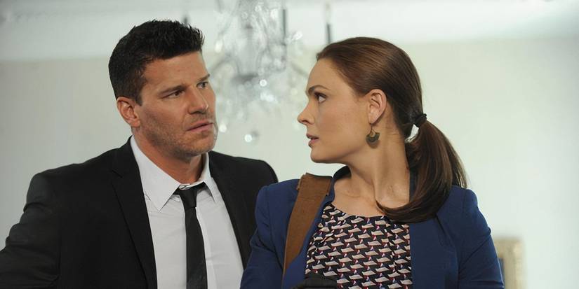 Booth, wearing a black suit, stands next to Brennan wearing a blue blazer in the TV show Bones