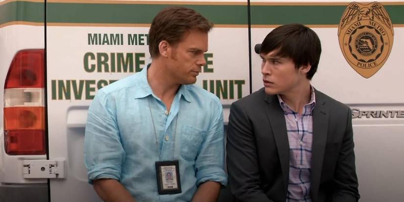 Dexter and Zach sitting against a Miami Metro truck looking at one another on Dexter.