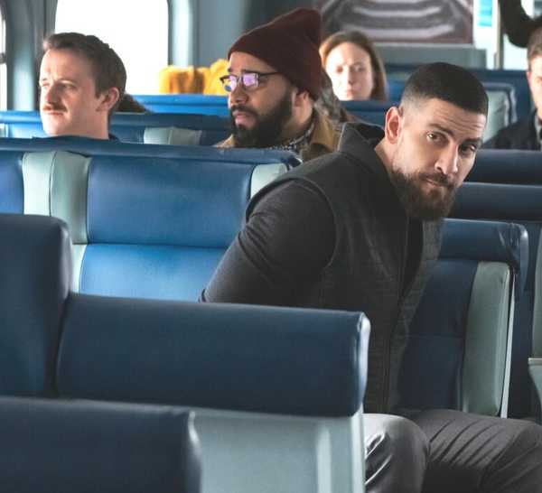 OA Zidan, played by Zeeko Zaki, wearing black jacket and looking over his shoulder on a train in FBI