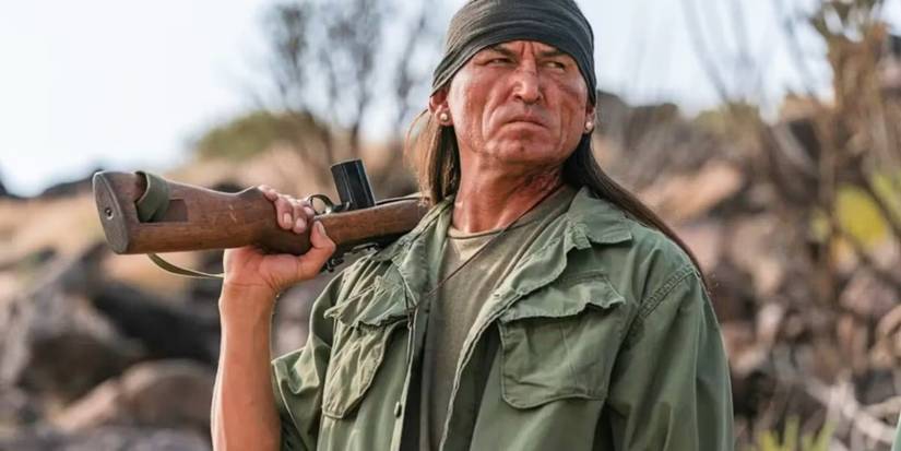 Frank Nakai with a gun slung over his shoulder in Dark Winds