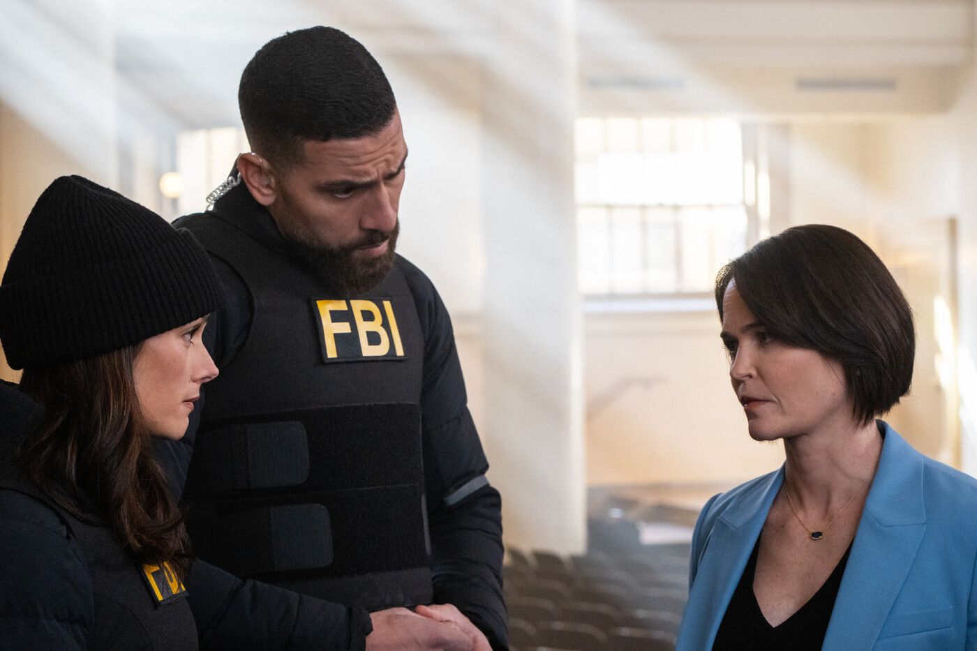 Maggie and OA, wearing FBI gear, speak with Aimee Fenway in a grey suit on the TV show FBI
