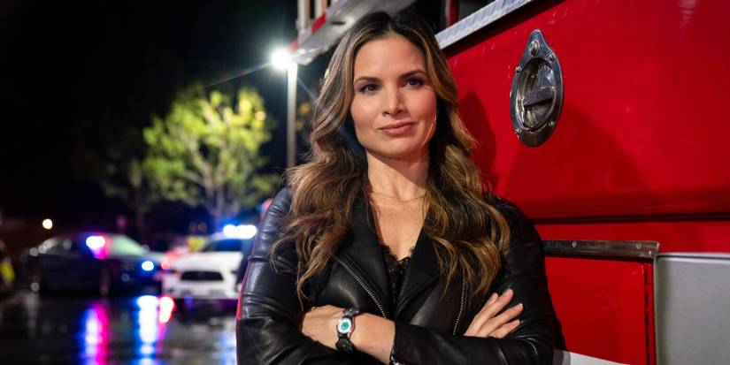 Jessica Knight wearing a black top, standing with arms folded next to a fire truck on NCIS