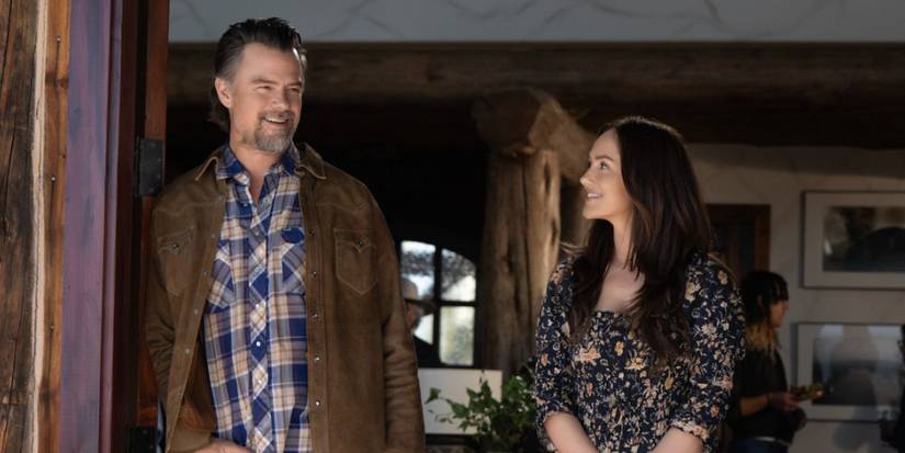 Josh Duhamel and Minka Kelly stand in a doorway, smiling at each other in Netflix's Ransom Canyon