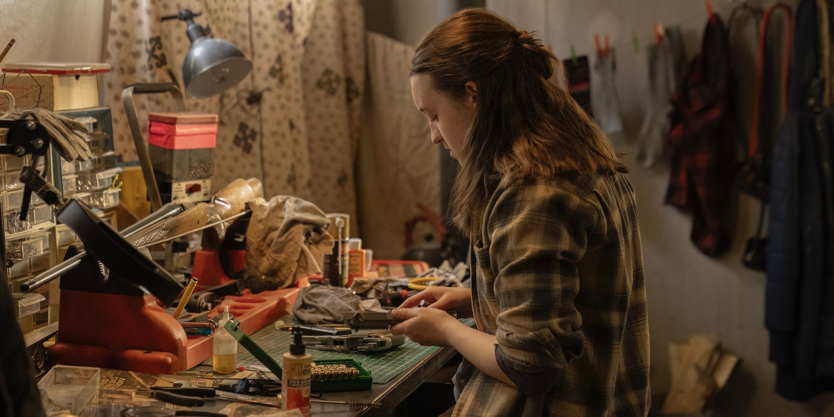 Ellie Williams (Bella Ramsey) cleaning a gun at a workbench on The Last of Us
