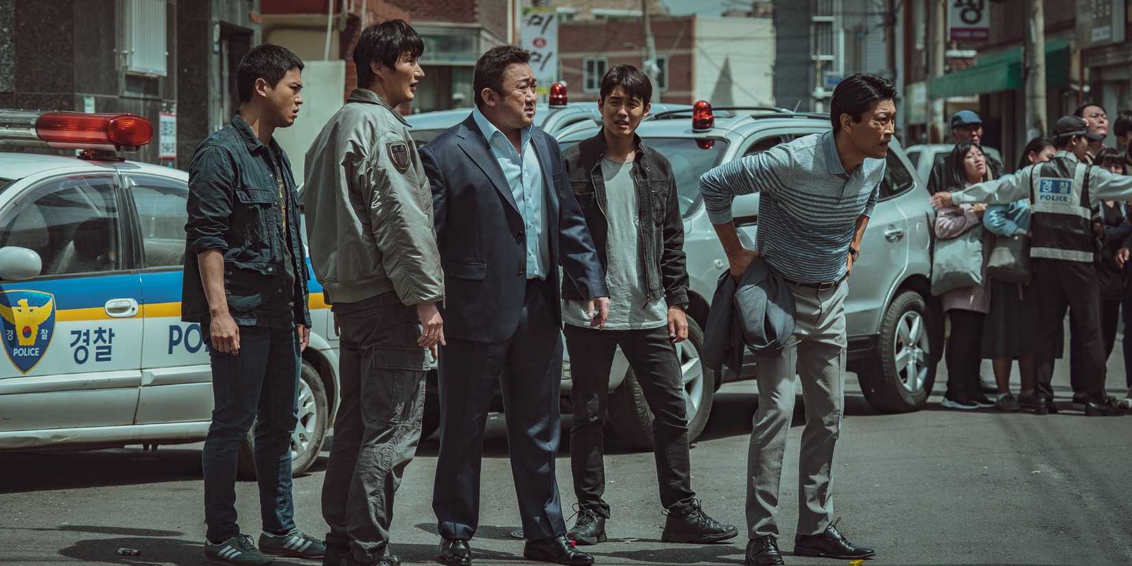 Ma Seok-do (Ma Don-seok) and other police offices look at something offscreen in The Roundup (2022)