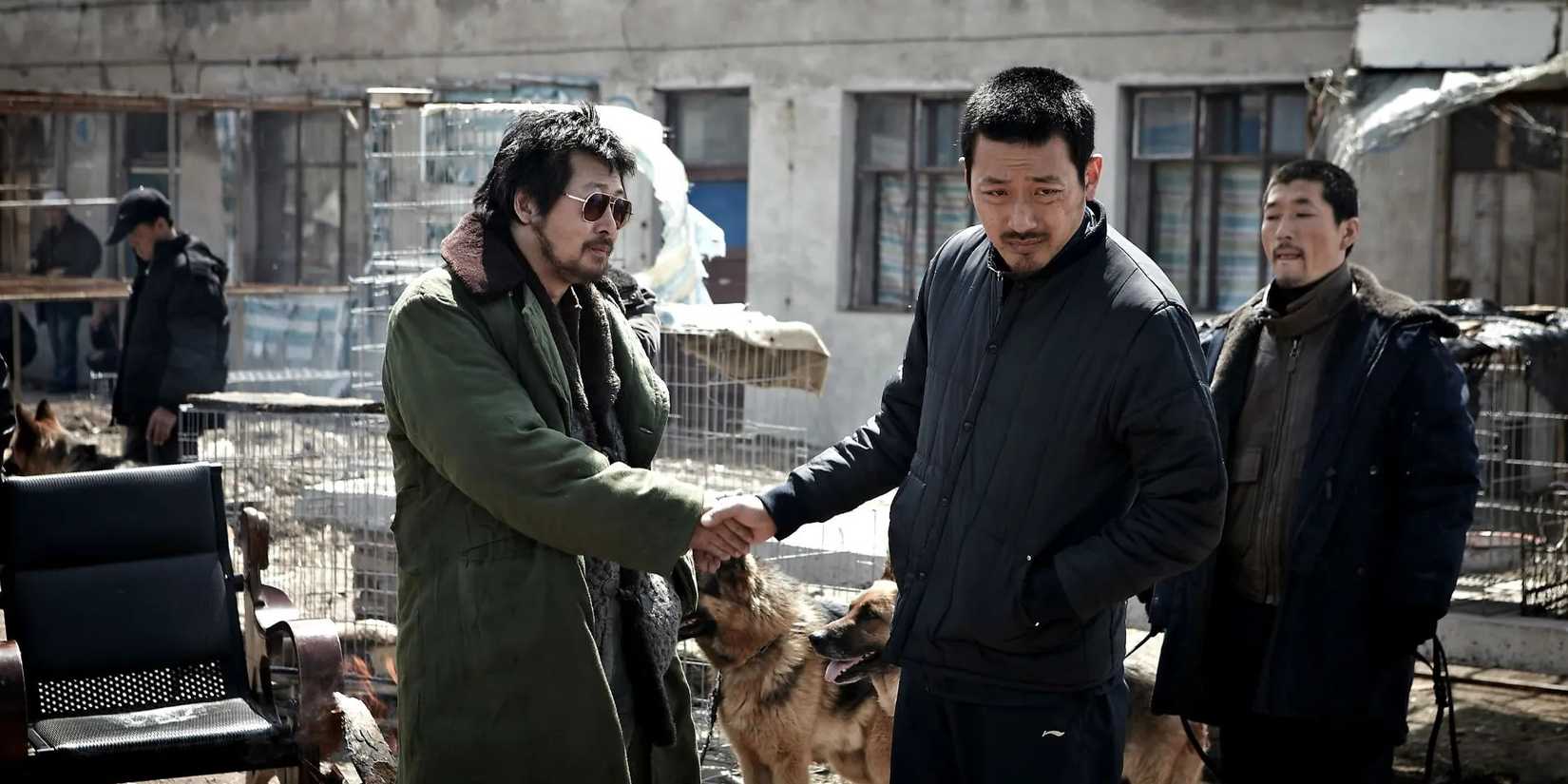 Two men shake hands outside beside two german shepherds in The Yellow Sea