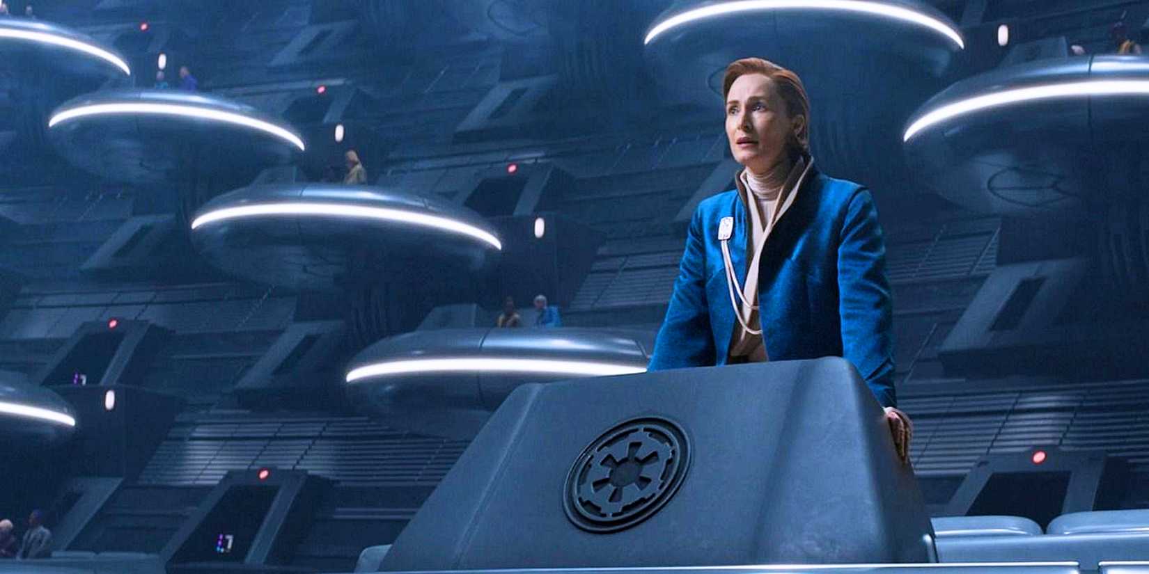 Mon Mothma in a blue robe standing in an Imperial senate hover pod from Andor