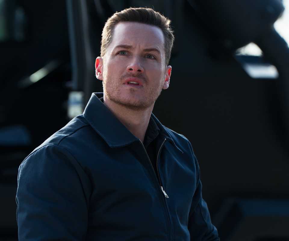 Wes, played by Jesse Lee Soffer, wearing a blue jacket next to an armored car in FBI: International