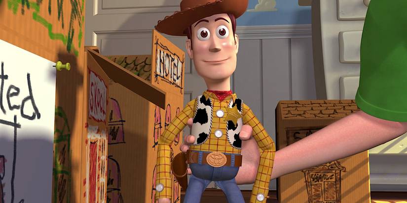 Andy's arm is moving Woody around a town made out of cardboard.