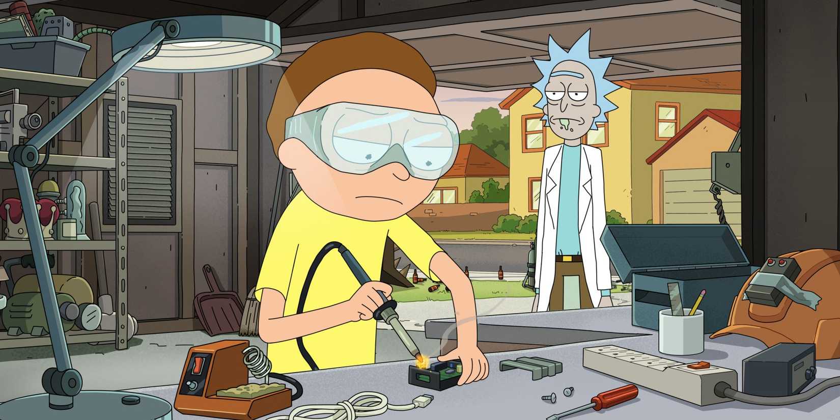 Morty, in a yellow shirt, sits in the garage welding as Rick stands in the doorway on Rick and Morty