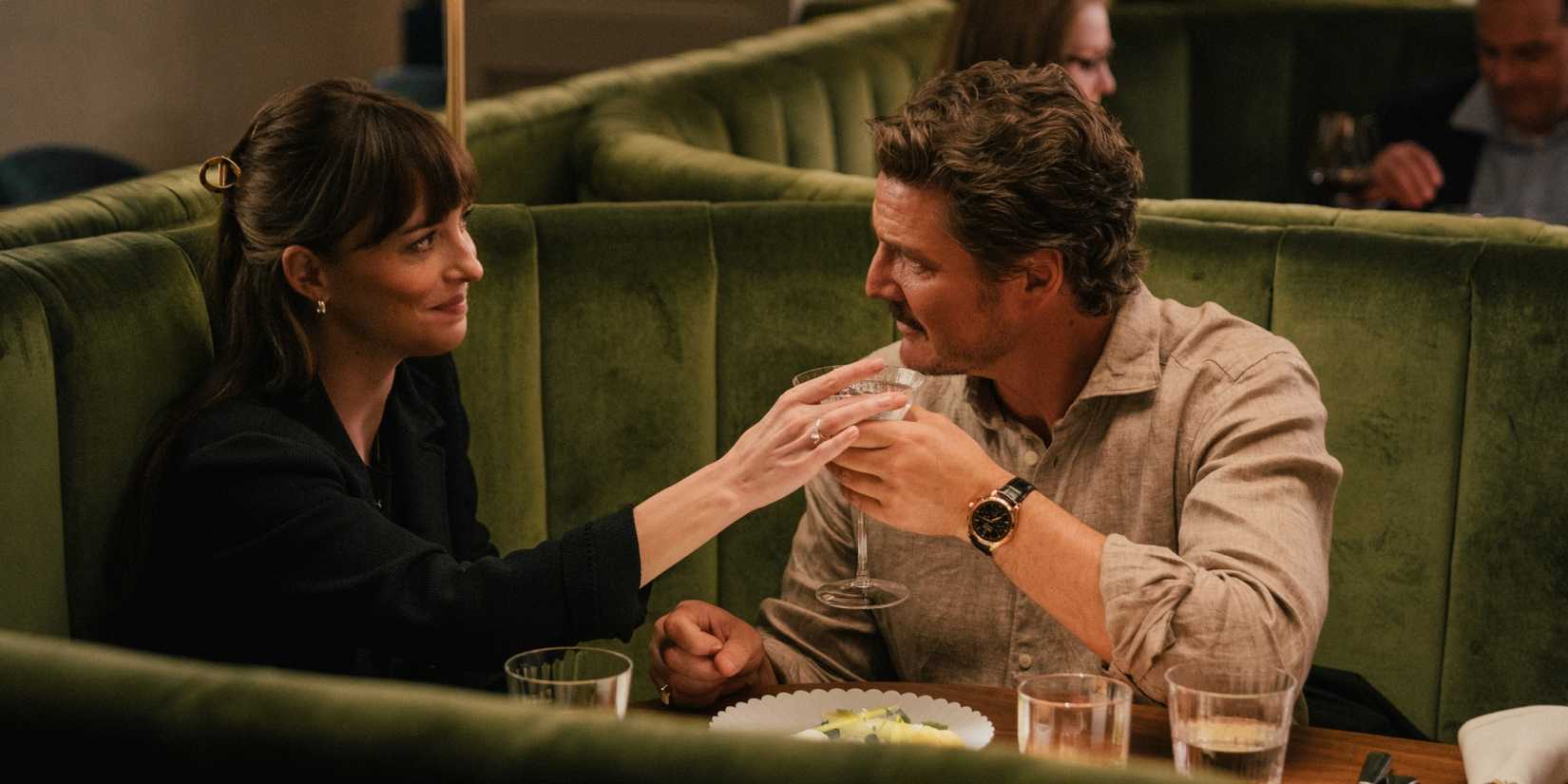 Dakota Johnson and Pedro Pascal holding a drink in Materialists