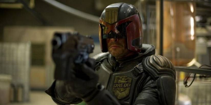 Karl Urban as Judge Dredd aiming a gun from the movie Dredd (2012)