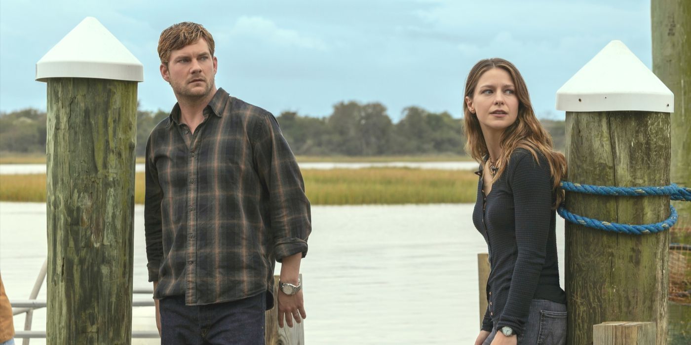 Cane, wearing a plaid shirt, stands on a dock next to Bree in black top in Netflix's The Waterfront