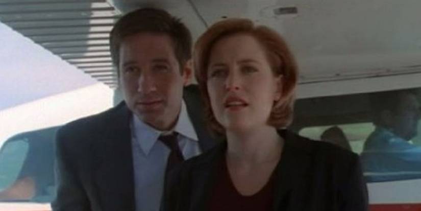 Fox Mulder (David Duchovny) and Dana Scully (Gillian Anderson) are squinting at something in The X-Files.