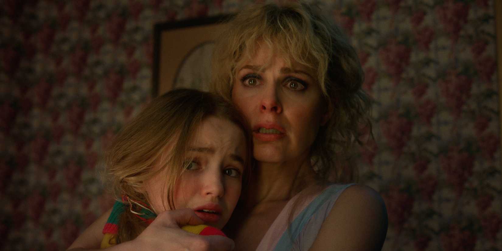 Holly (Nell Fisher) and Karen Wheeler (Cara Buono) hugging and looking scared in Stranger Things Season 5.