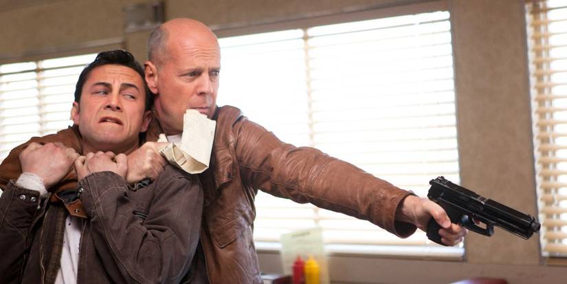 Joseph Gordon-Levitt as Joe and Bruce Willis as Old Joe pointing a gun from the movie Looper (2012)