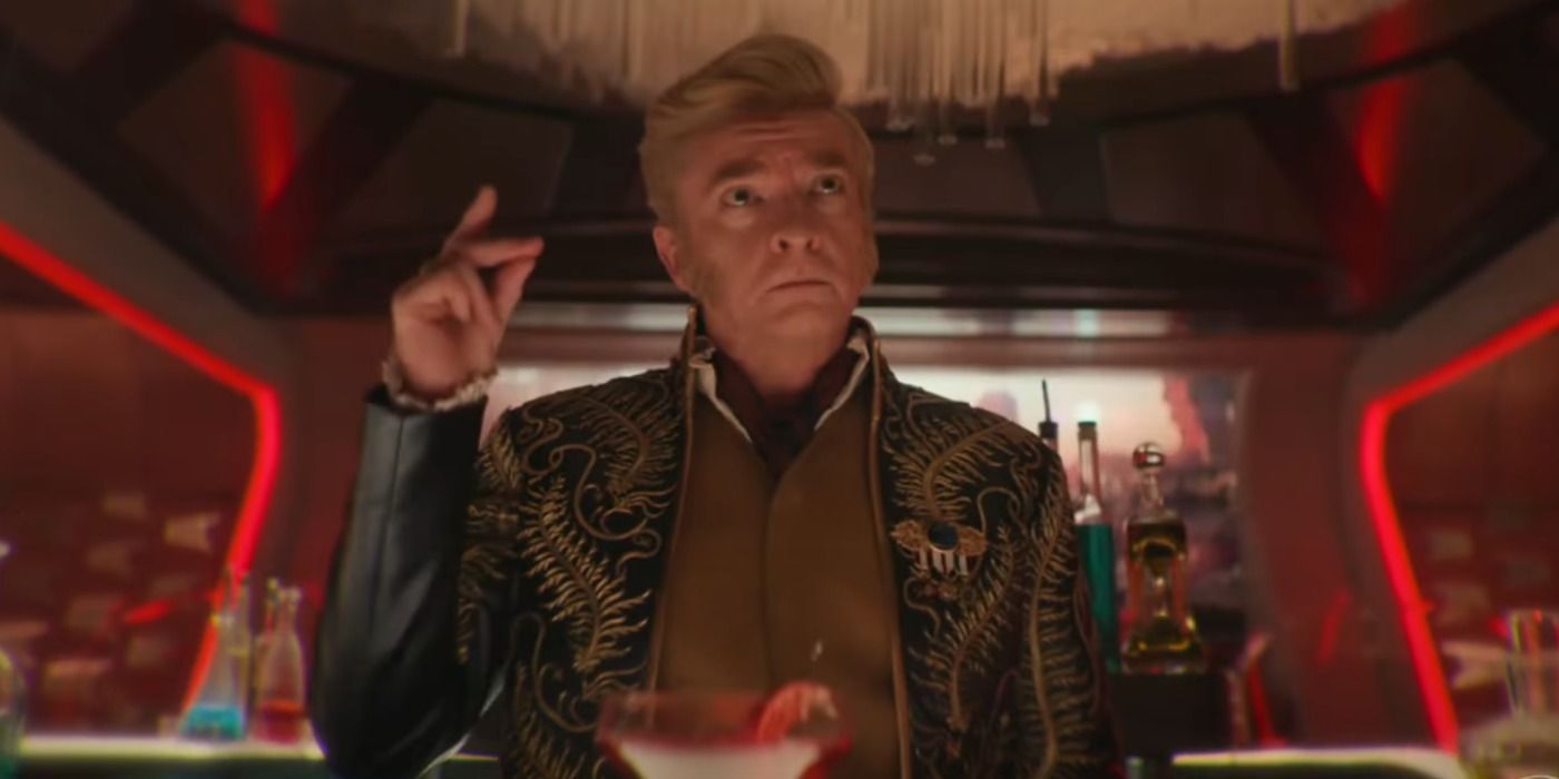 Rhys Darby in an ornate coat behind the Enterprise bar about to snap his fingers from Star Trek Strange New Worlds