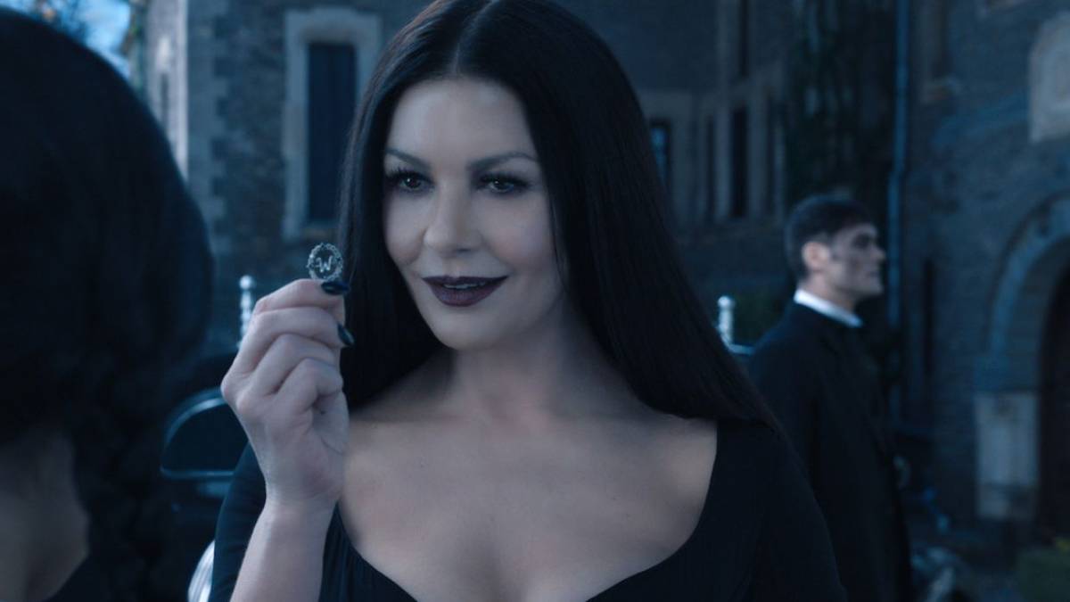 Morticia showing Wednesday something in her hand.