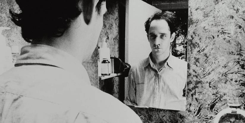 Max stares at himself in a mirror in Darren Aronofsky's Pi