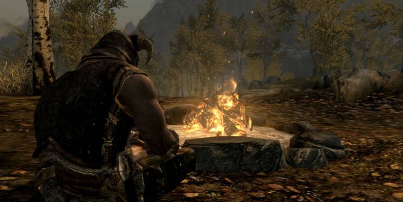 The Dragonborn in Skyrim is sitting by a campfire.