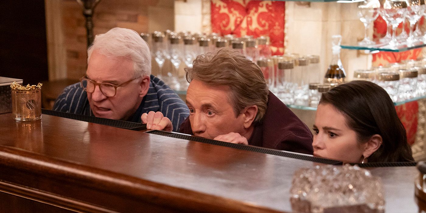 Charles, Oliver, and Mabel peaking from behind a bar in Only Murders in the Building.