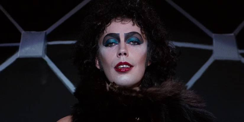 A closeup of Tim Curry as Dr, Frank N Furter wearing fur during a solo in The Rocky Horror Picture Show