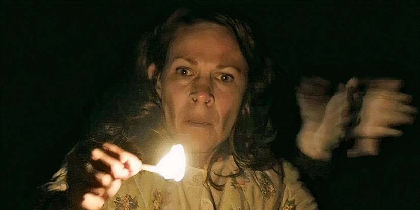 Carolyn Perron holds a match while a pair of hands slammed behind her in conjuration