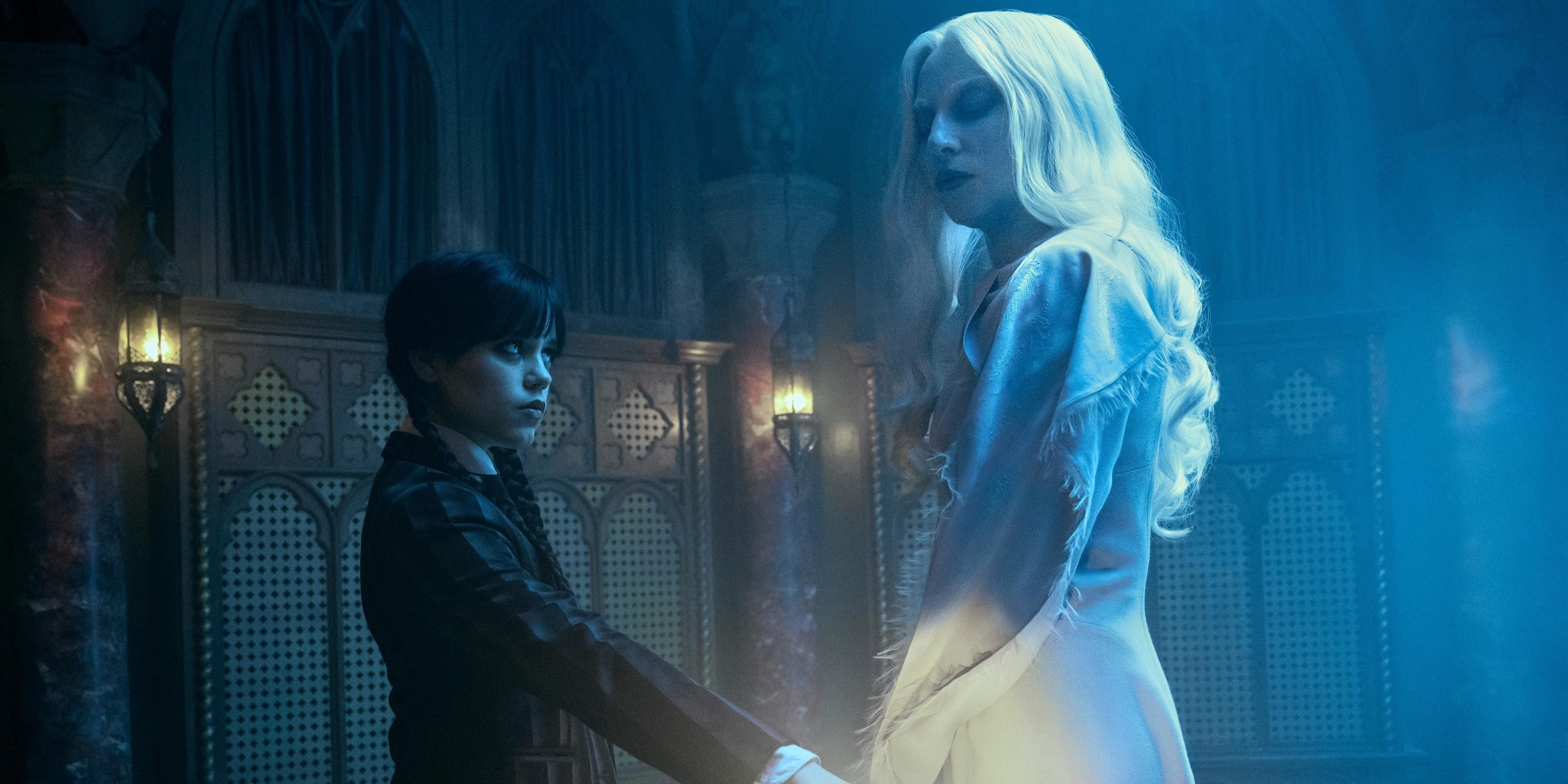 Wednesday Addams (Jenna Ortega) holding her hand over a candle as Rosaline Rotwood (Lady Gaga) watches in Wednesday.