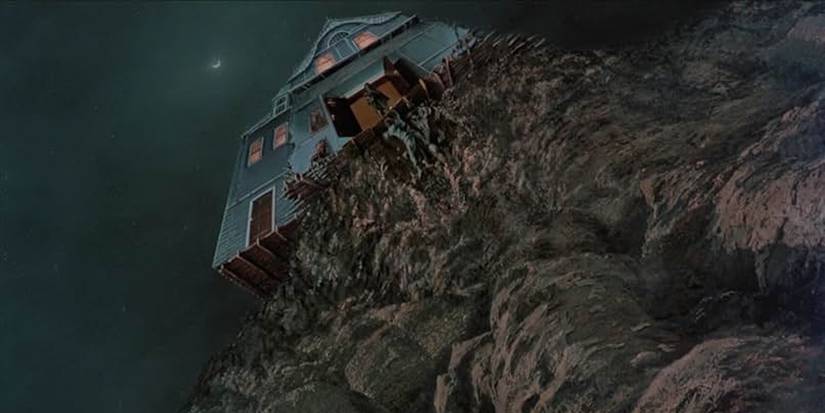 Arthur Cobb (William Katt) stands precariously at the edge of the cliff where his home is suddenly located.