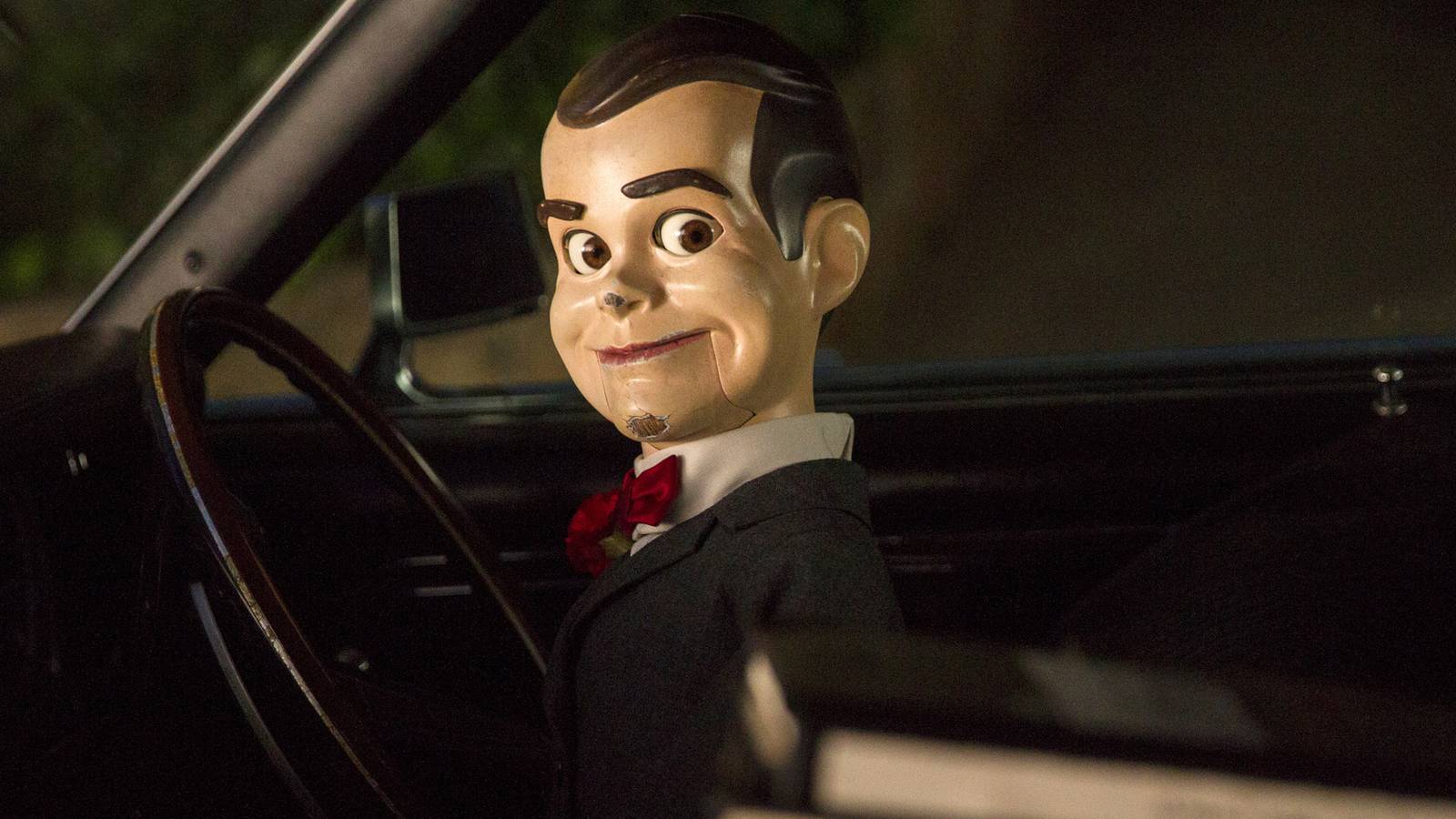 Slappy the Dummy next to a pile of books in a car from Goosebumps