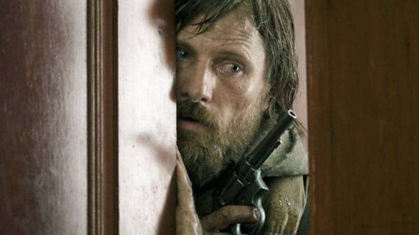 Man looks through the crack in a door in The Road