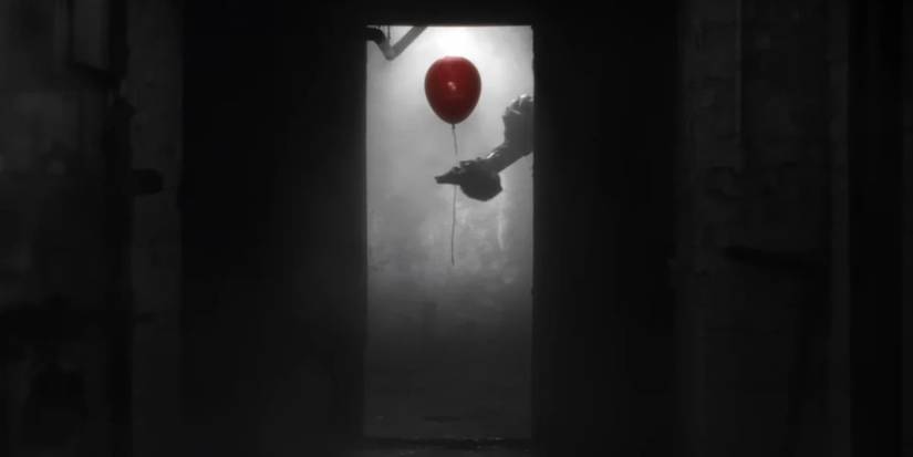 Pennywise's hand holding a balloon in an open doorway