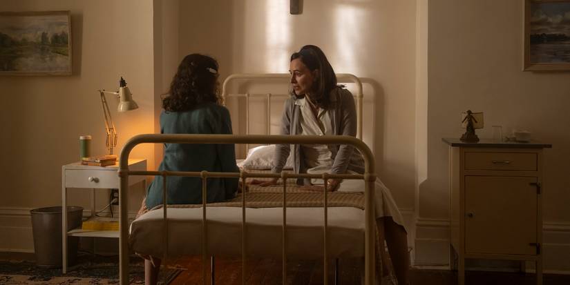Ingrid Kersh and Lilly Bainbridge talk while sitting on a bed in Juniper Hill in Welcome to Derry Episode 3