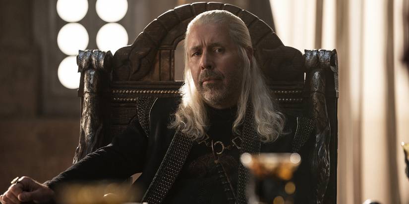 King Viserys I Targaryen sits at a table, deep in thought, in House of the Dragon