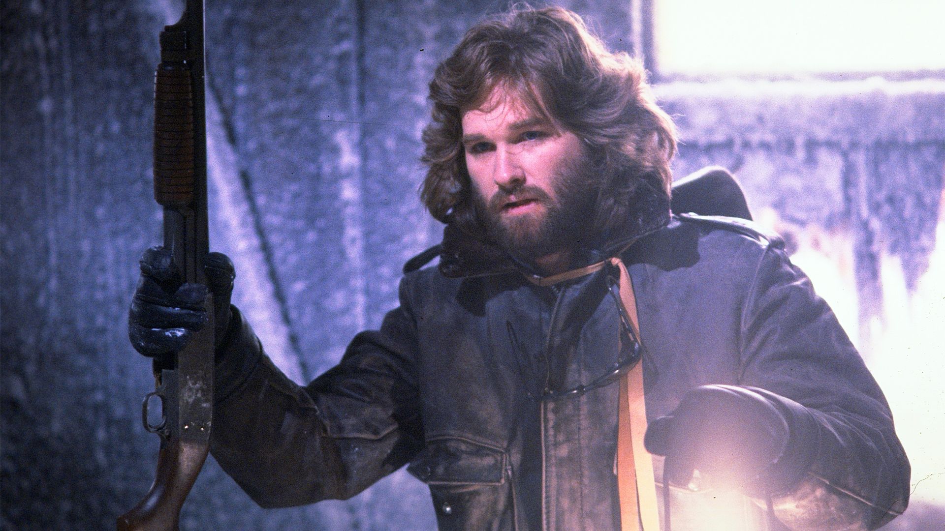 Kurt Russell holding a shotgun and a lantern in The Thing