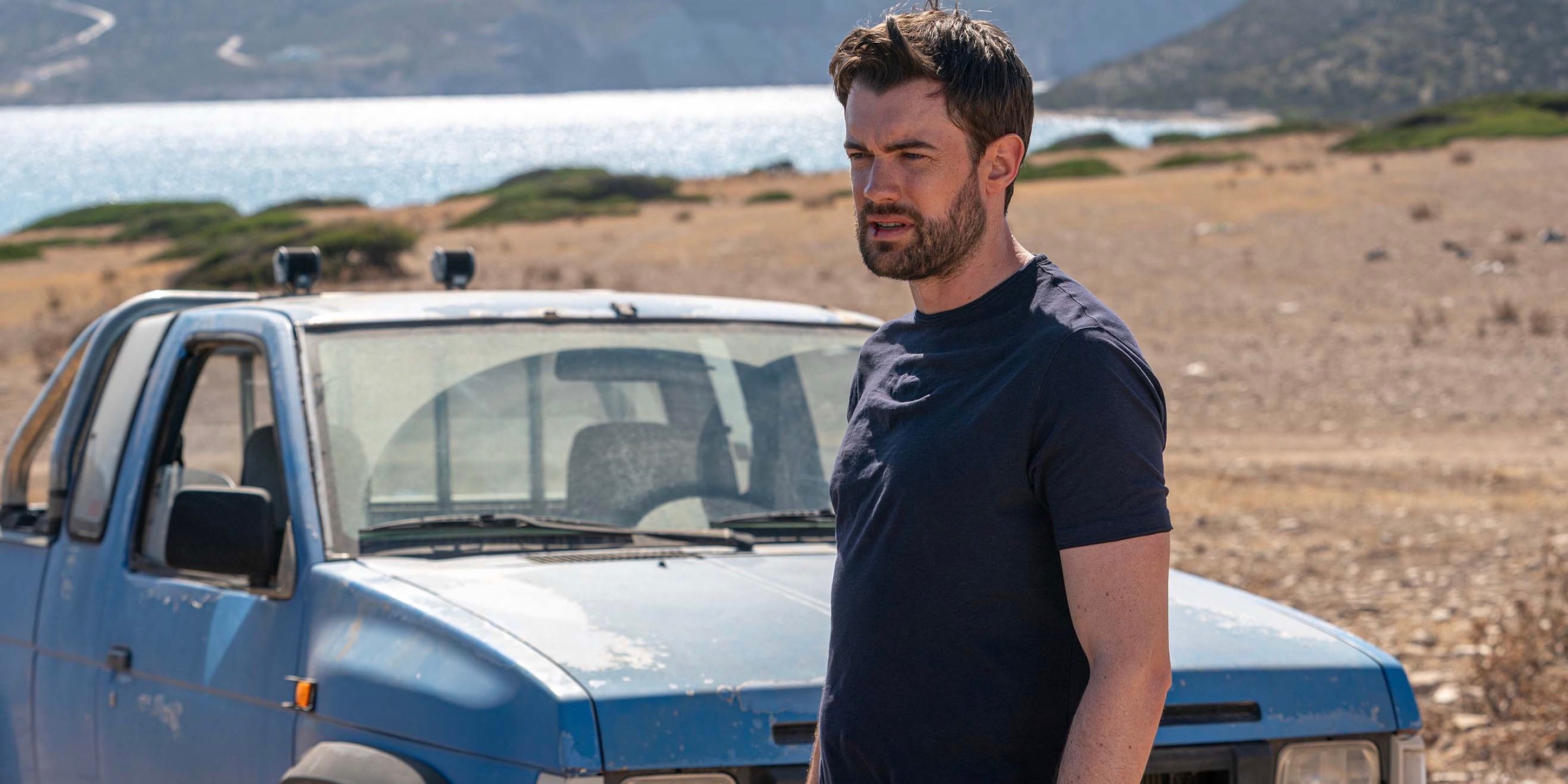 Jack Whitehall as Adam Healey on the beach in front of a blue truck on Malice