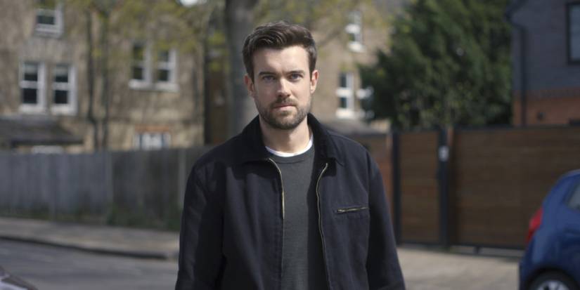 Adam Healy standing on the street of a British suburb, looking at the camera in Malice