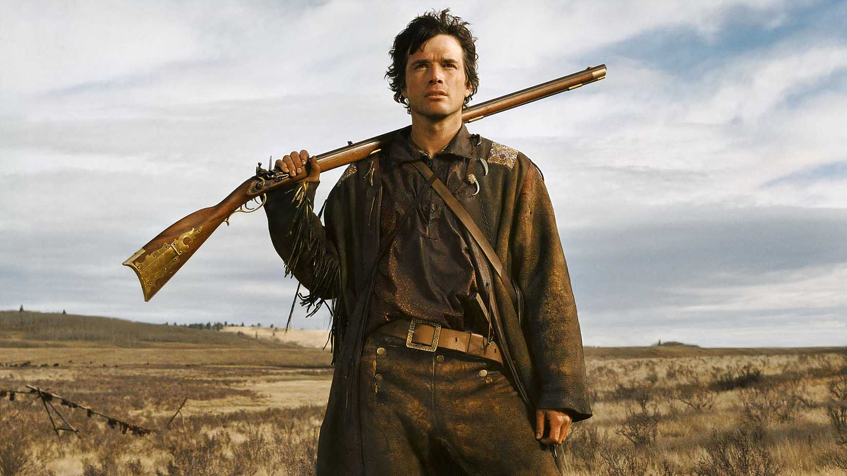 Matthew Settle in Into the West, holding a rifle in a meadow