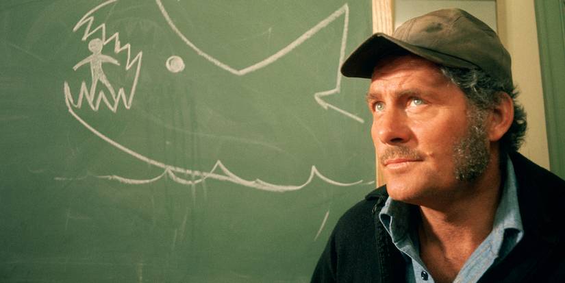 Quint sits in front of a chalkboard with a shark drawing in Jaws 1975