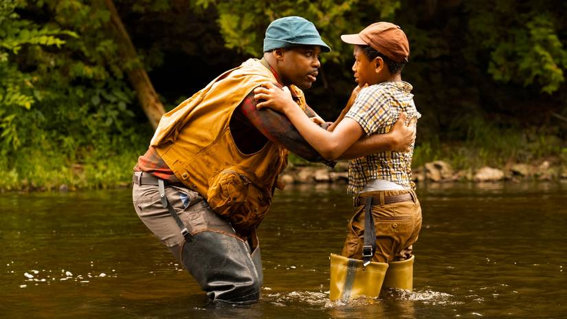 Standing in a river, Leroy checks on his son, Will, following an attack by Pennywise in IT: Welcome to Derry Season 1 - Episode 4