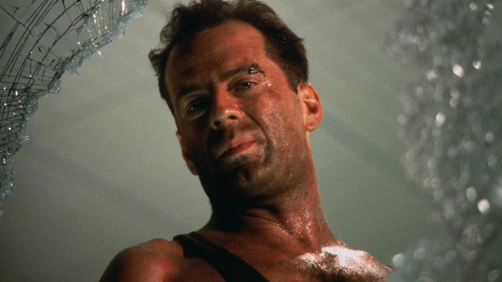 Bruce Willis looks out a broken window in Die Hard