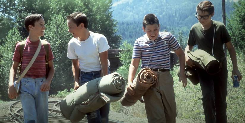 The boys walk along railroad tracks, laughing, in Stand By Me