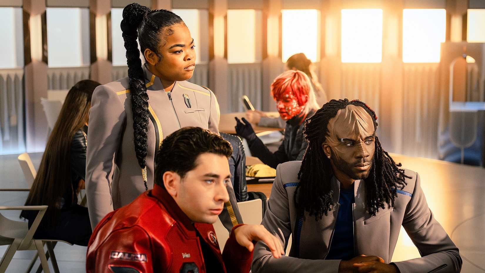 SAM standing as Ocam and Jay-Den sit at a table from Star Trek Starfleet Academy